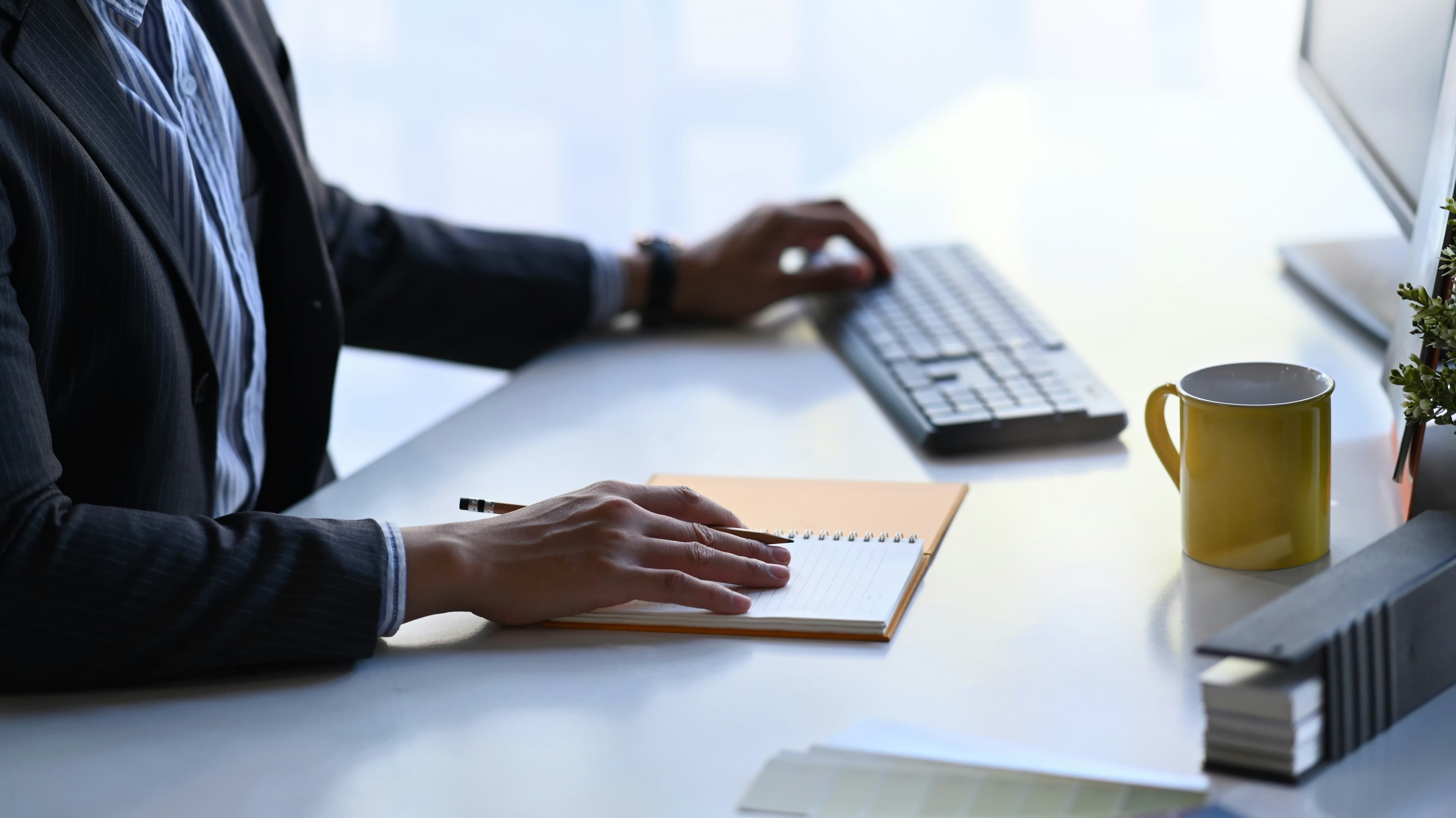Investigator writing notes at a desk beside a keyboard