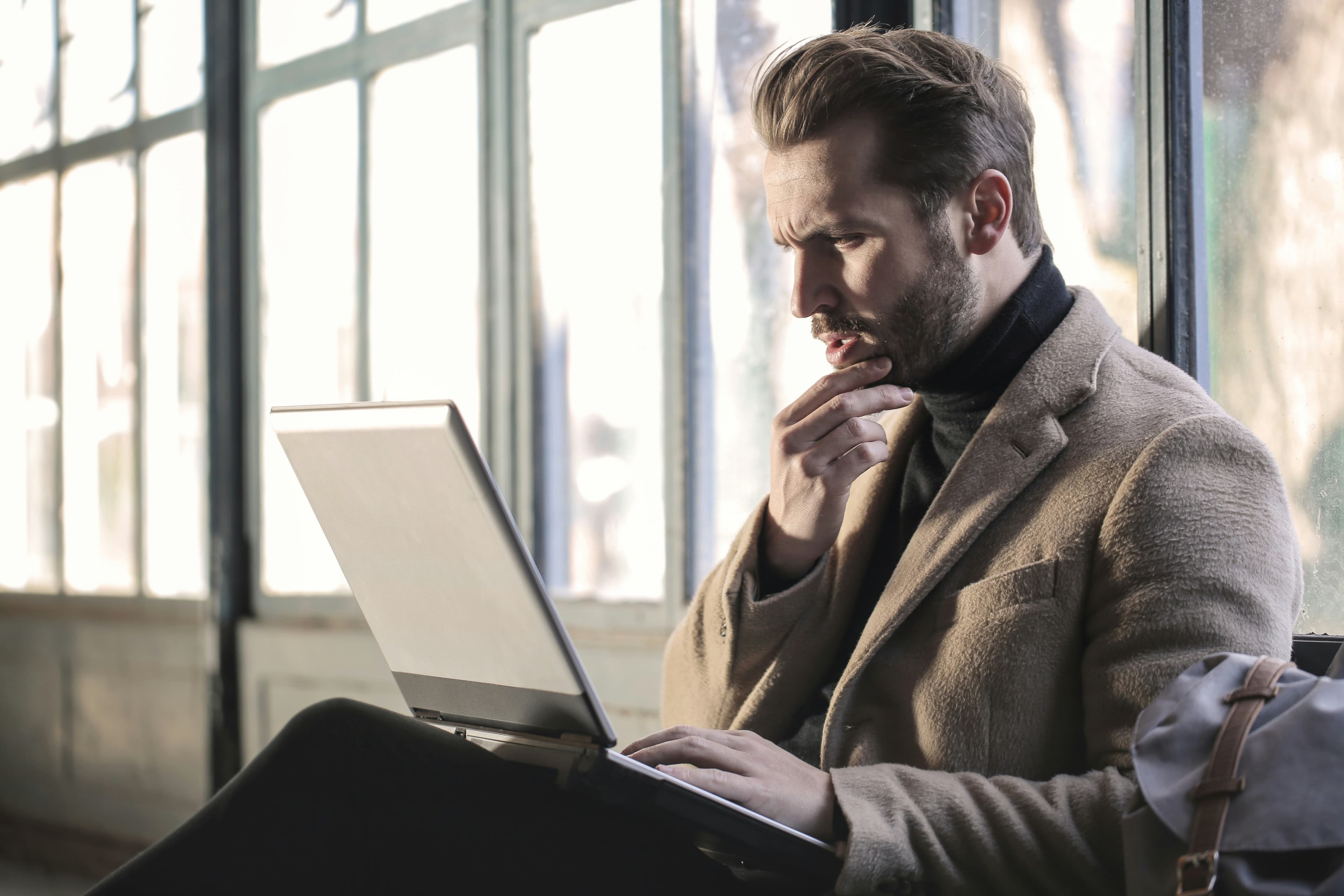 Investigator reviewing documents on a laptop near a window